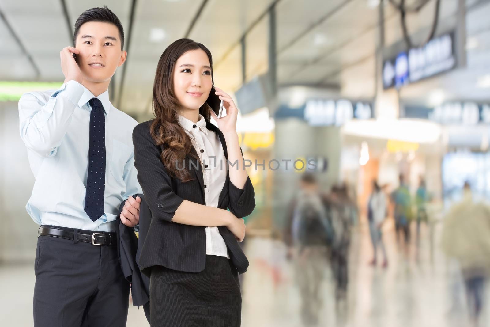 Asian business man and woman talking on cellphone in the station of Hong Kong, Asia.