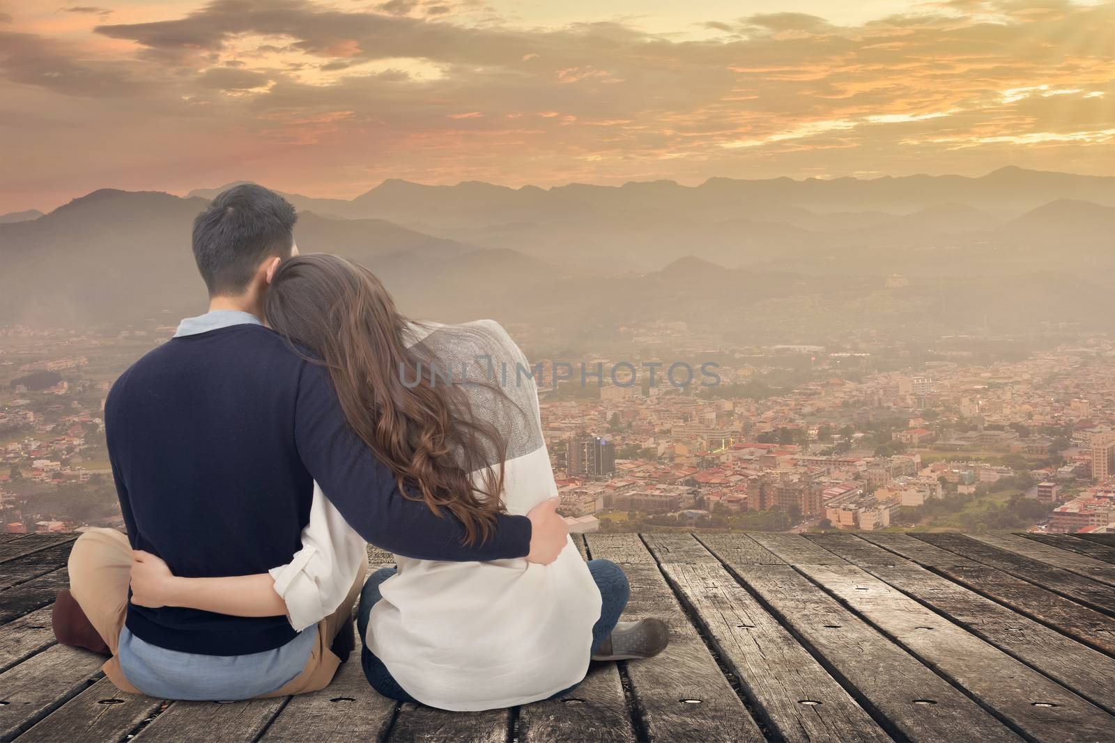 Asian young couple sit and hug together against the sky in outdoor.