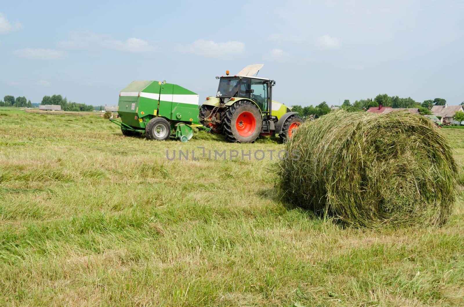 tractor bailer collect hay in agriculture field by sauletas