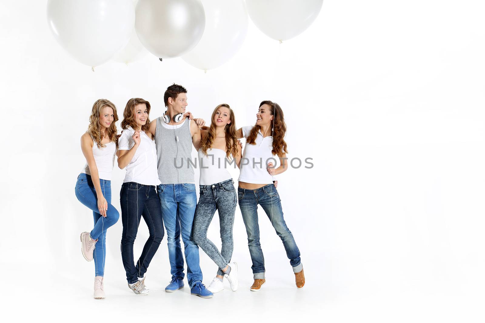 The team of five young people dressed in white shirt and jeans posing with giant balloons