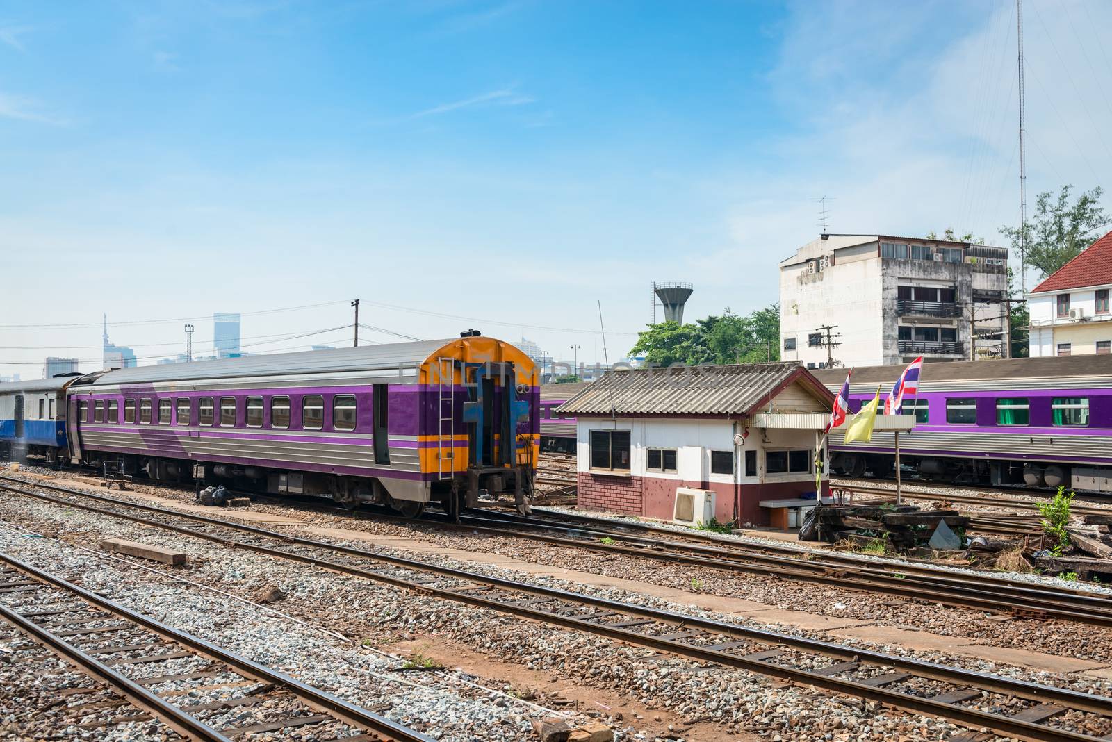 Trains stand at railway transport interchange with Thailand flags and big city buildings on background