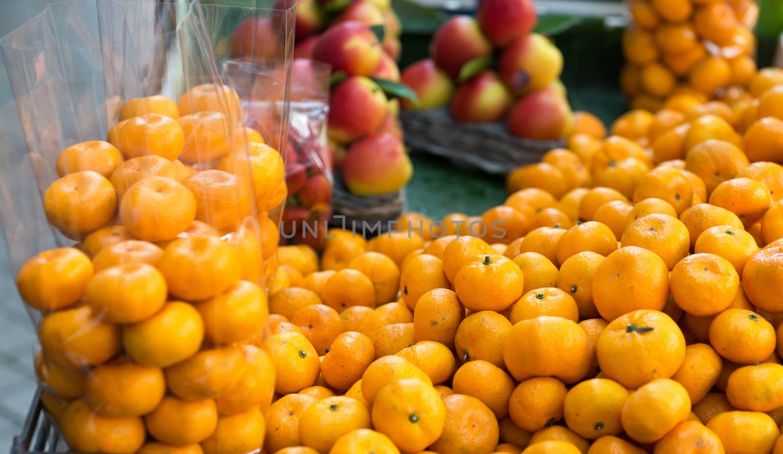 Small open street counter with fresh mandarin fruits partly packed in bags and apples on background