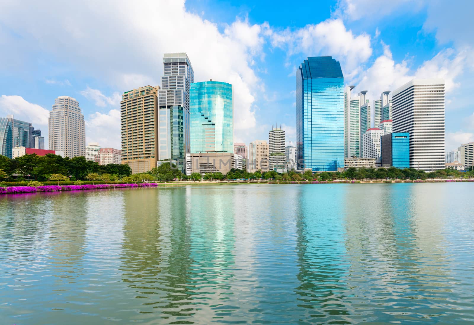Modern city skyline of business district downtown with reflection in lake water in day under blue sky