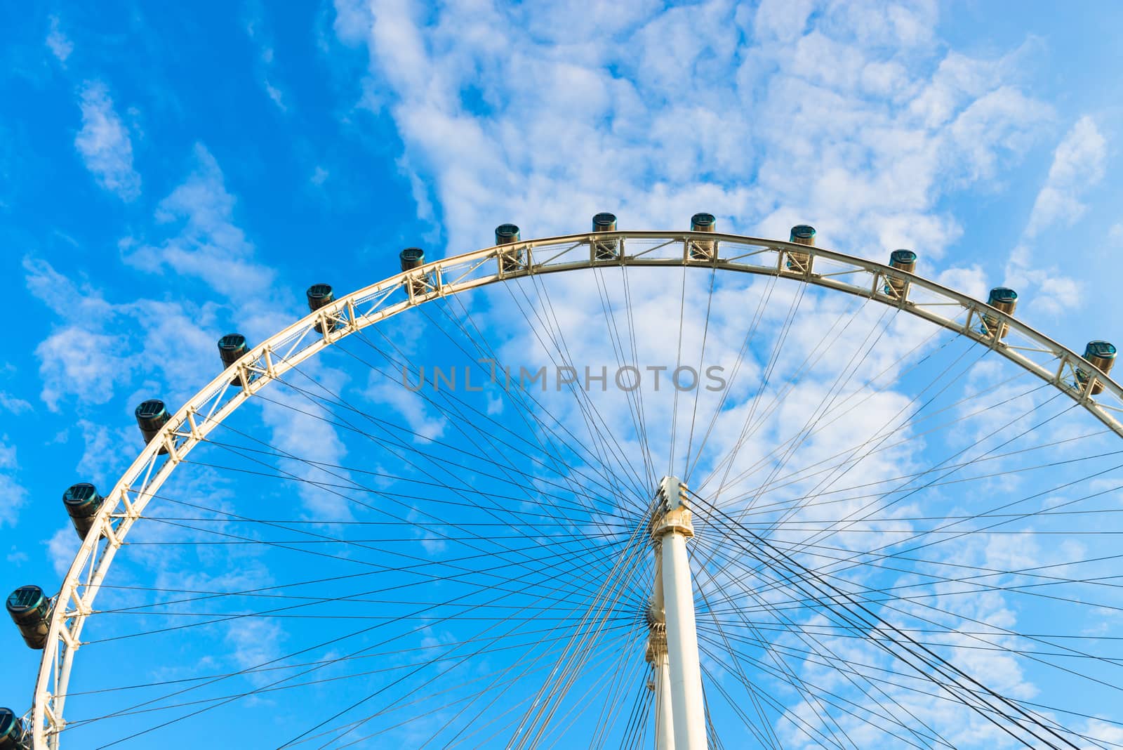 Big ferris wheel with cabin on blue sky with white clouds