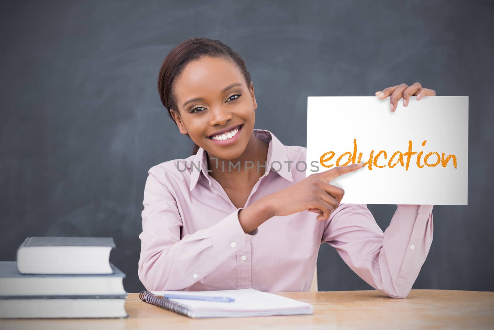 Happy teacher holding page showing education by Wavebreakmedia