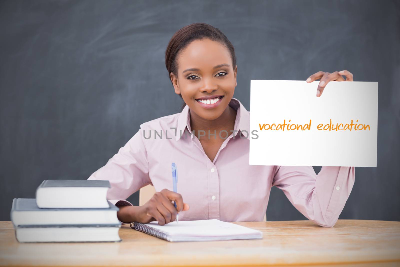 Happy teacher holding page showing vocational education in her classroom at school