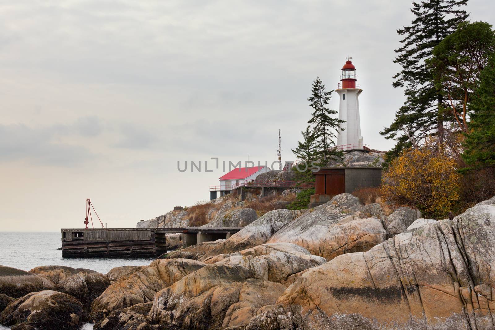 Coastal granite rock cliff with lighthouse building and communications antennas on British Columbia West Coast north of Vancouver, Canada