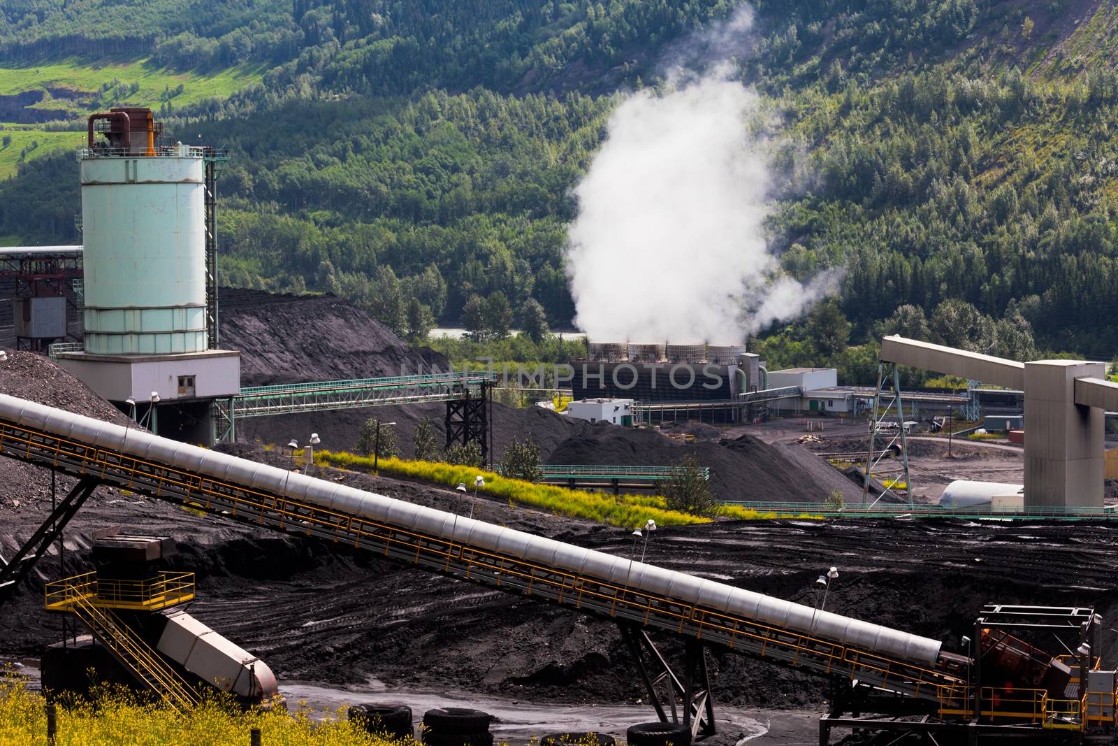 Black coal mine pile at coal fired electrical energy power station in green valley contributes to global warming