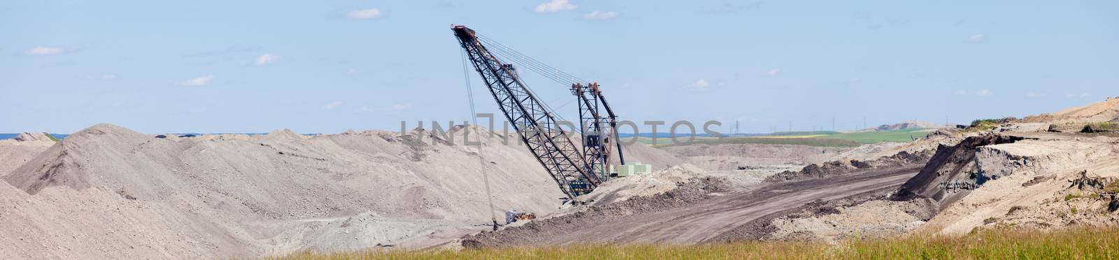 Coal mine industrial excavator machinery equipment among moon-like tailings landscape panorama in Alberta, Canada