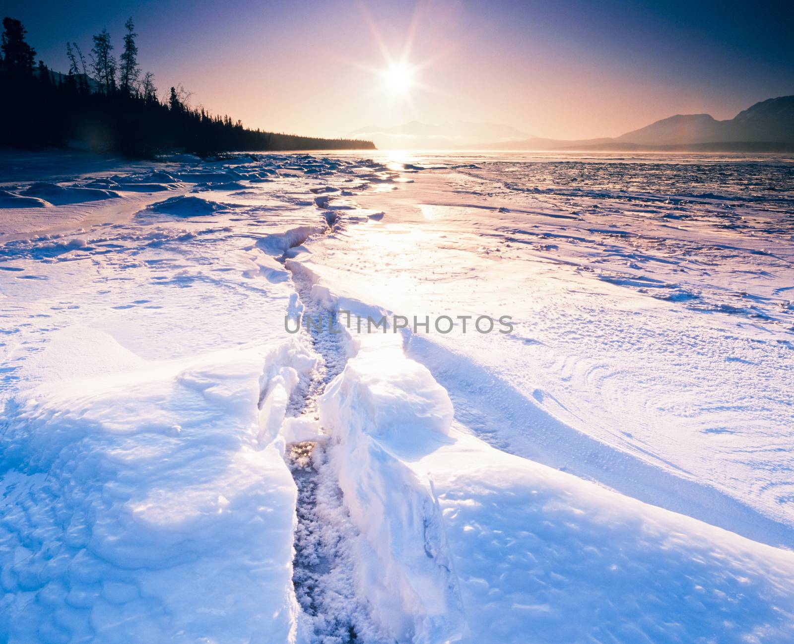 Low winter sun over large crevasse in shore ice of frozen Tagish Lake, Yukon Territory, Canada