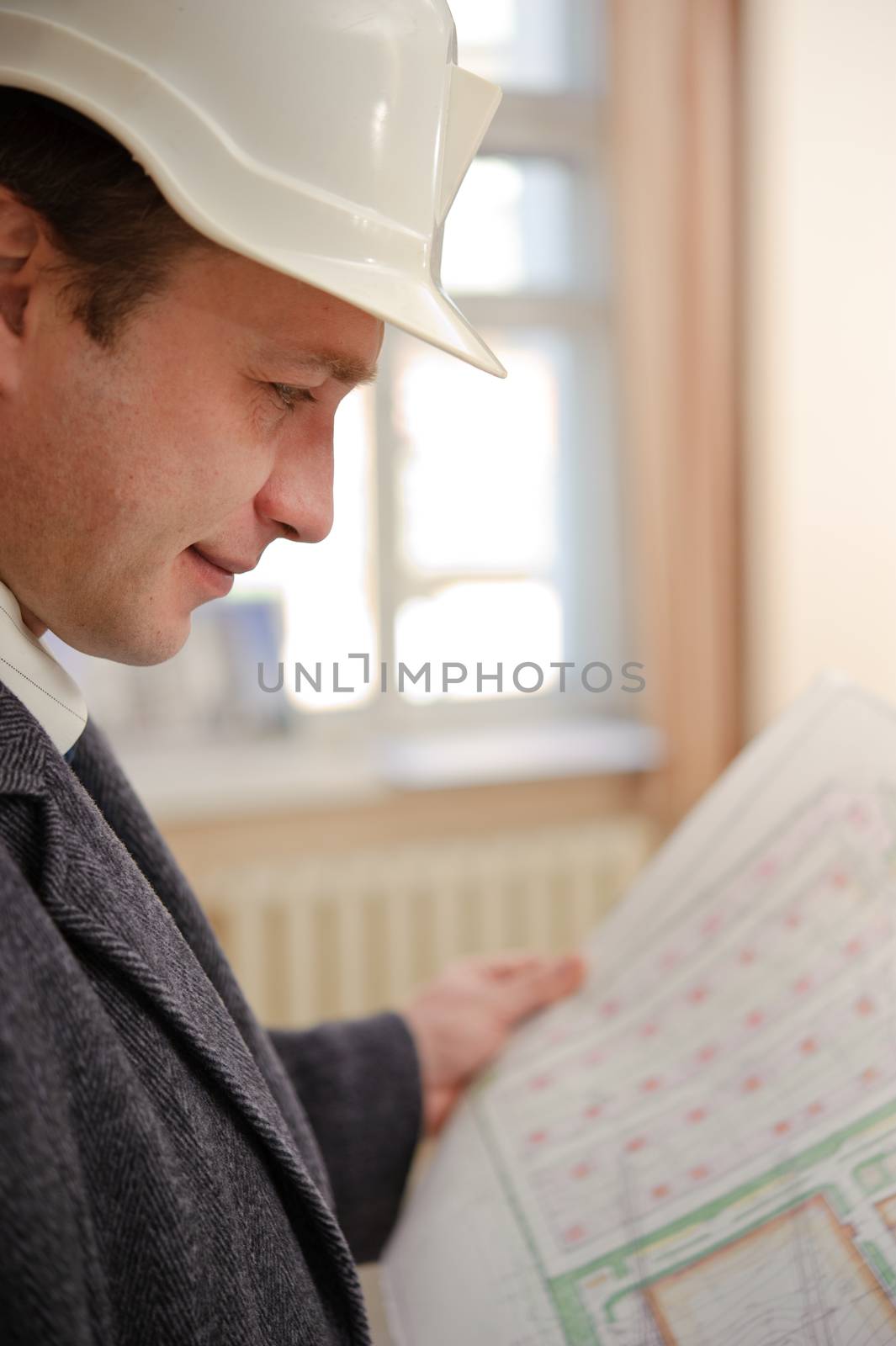 Engineer or architect with a hard hat, looking at plans.