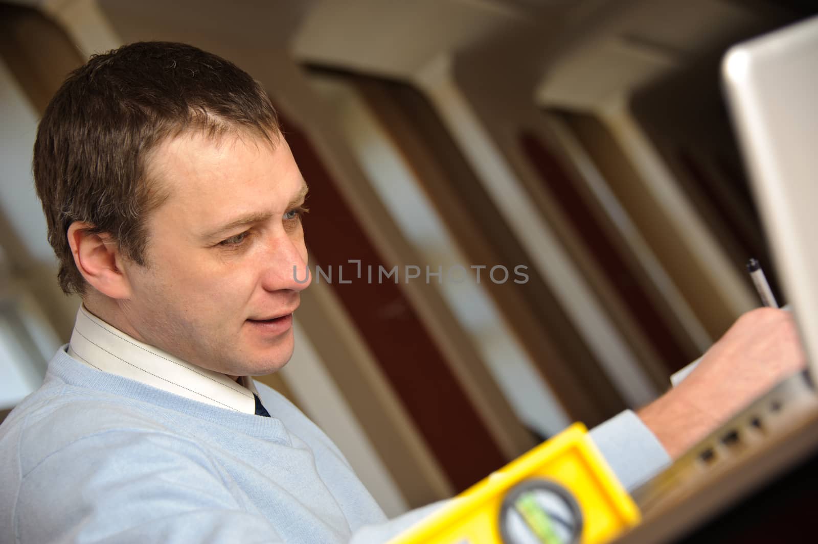 Portrait of engineer or architect in blue pullover is working on construction plans.