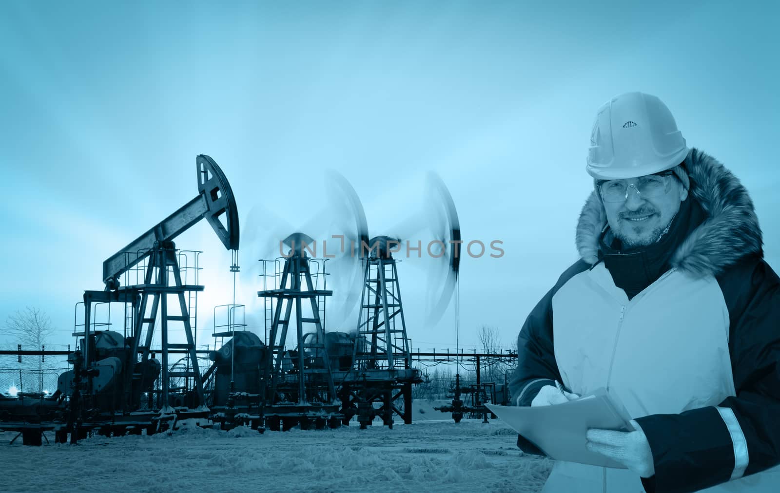 Oil worker in uniform and helmet on of background the pump jacks and sunset sky. Monochrome.