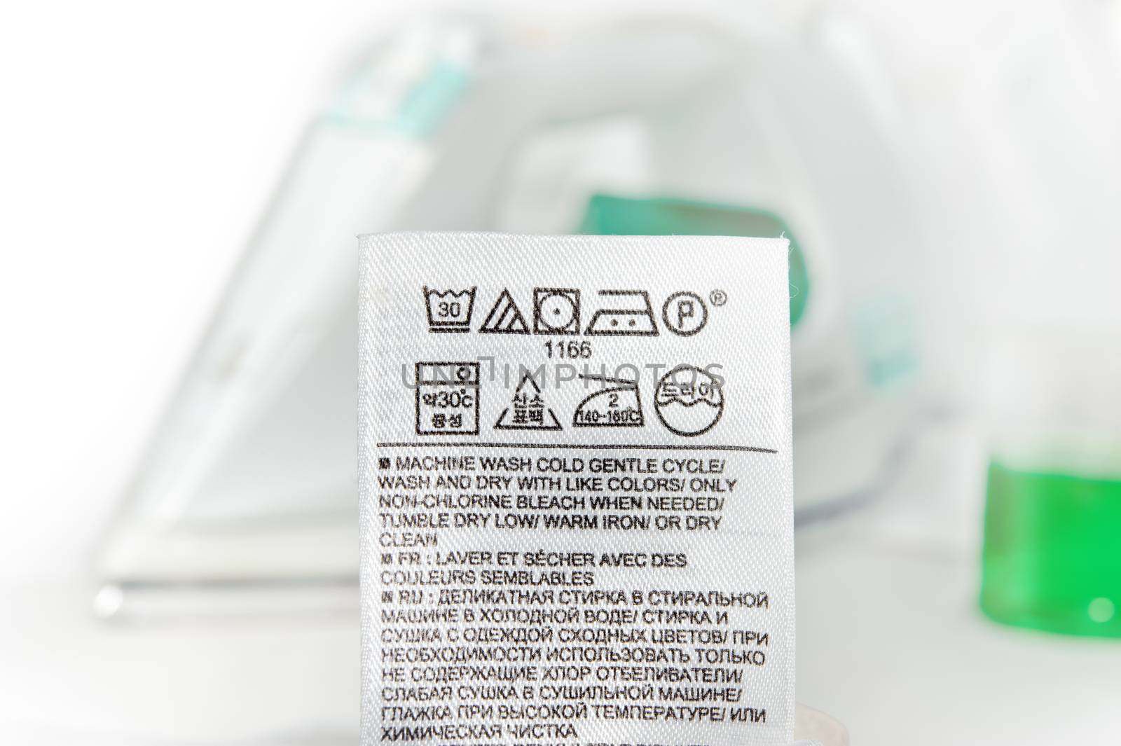 Clothes label with cleaning instructions on a steam iron background.