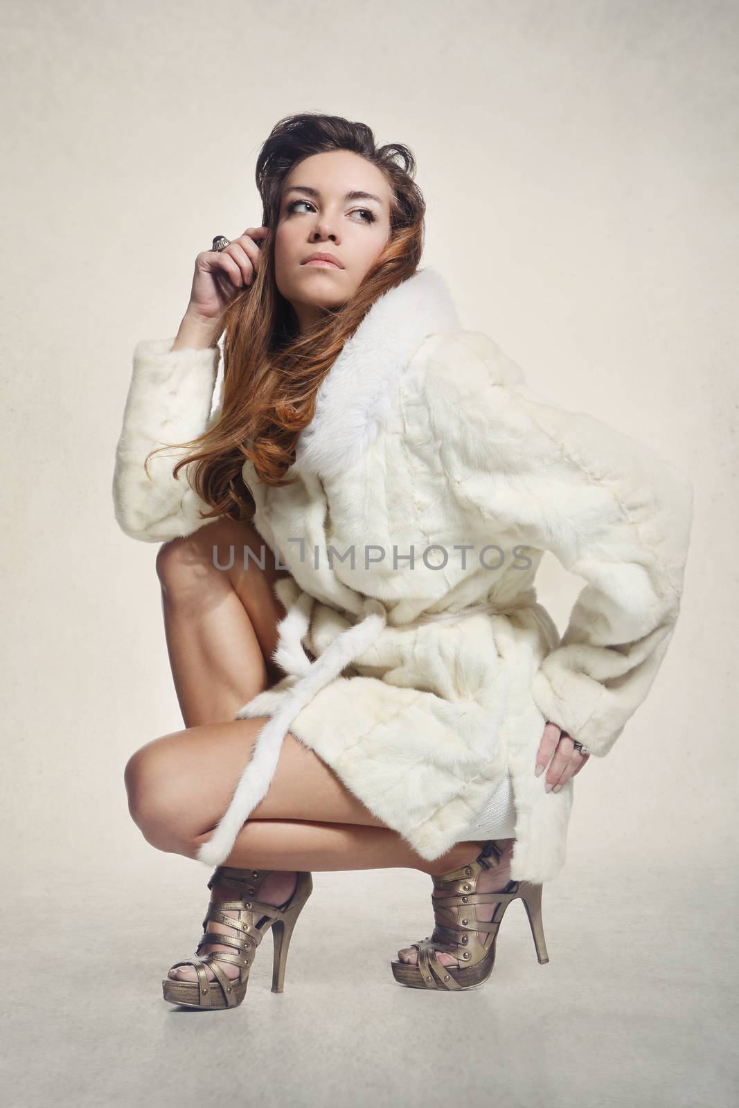 Sexy female model in a luxurious white fur coat