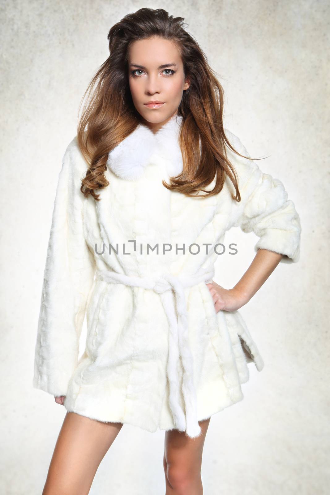 Brunette fashion model in white fur posing on a white background