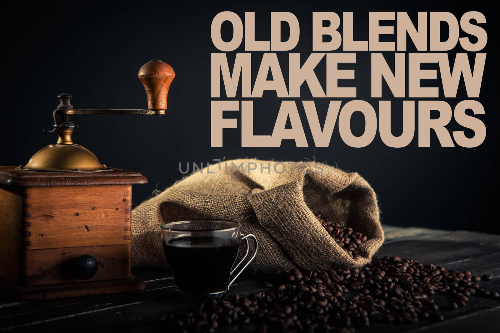 tools for preparation of coffee. an old grinder a sack made by jute full of coffee beans and cup of black coffee on a wooden table. text on file for print use