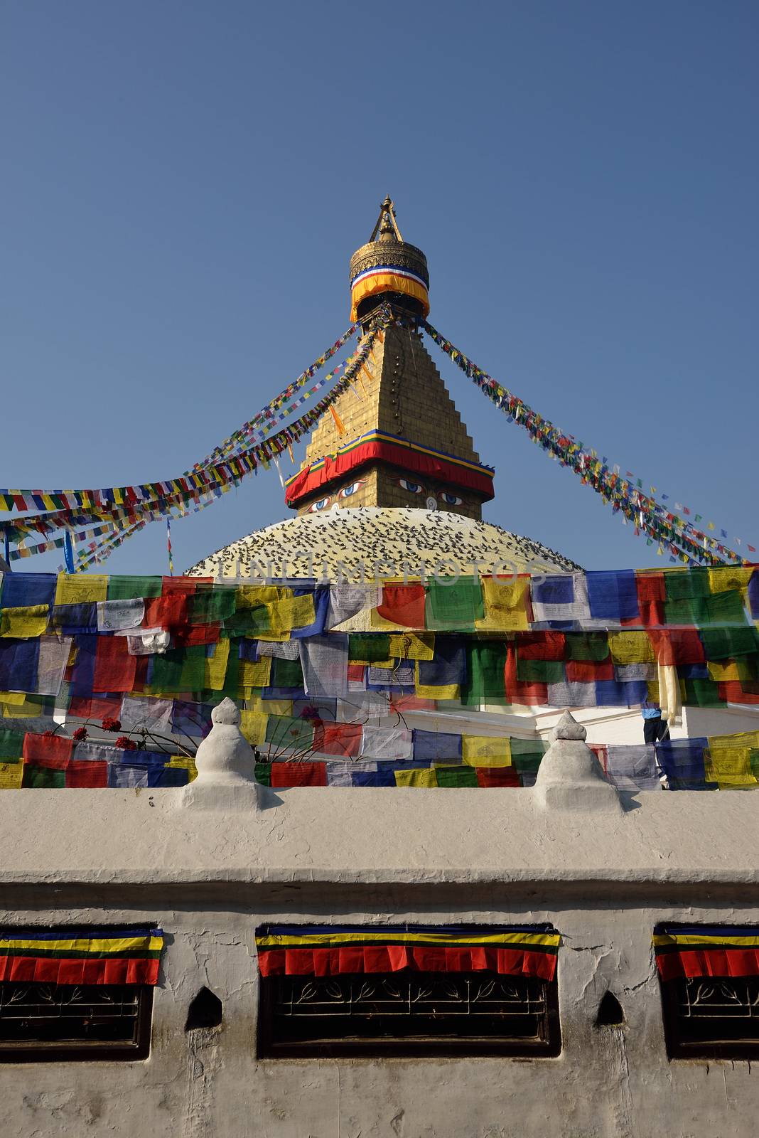 Buddhist Shrine Boudhanath Stupa with pray flags over blue sky. by think4photop