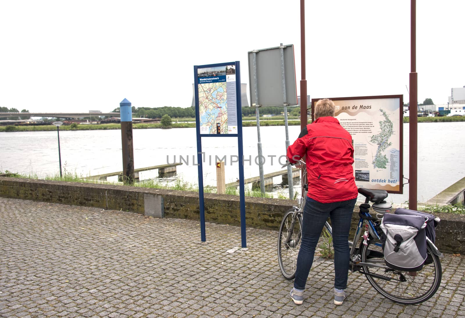 woman looking at information board near the river maas in Holland
