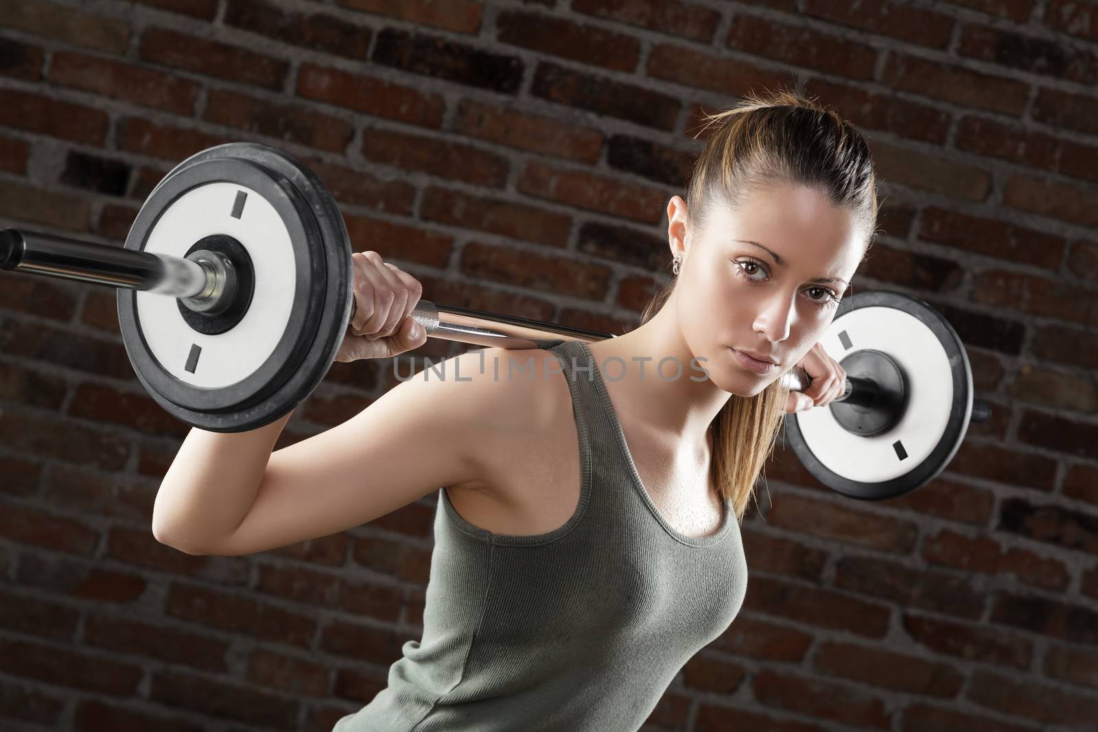Portrait of Sweat fit woman lifting dumbbells on brick background 