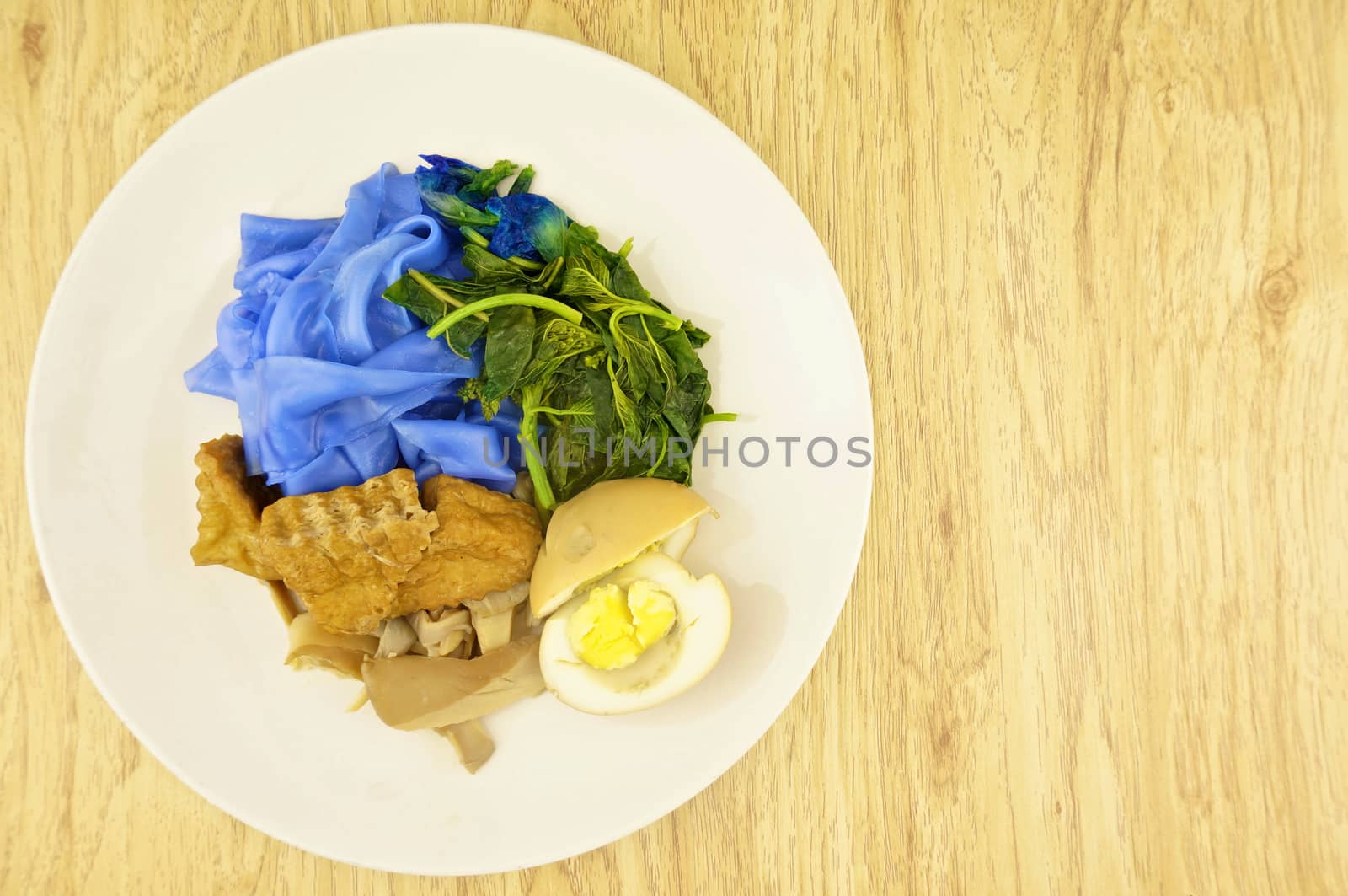 Blue rice noodle with fried tofu, spinach, abalone mushroom and egg boiled in the gravy vegetarian on wood background.