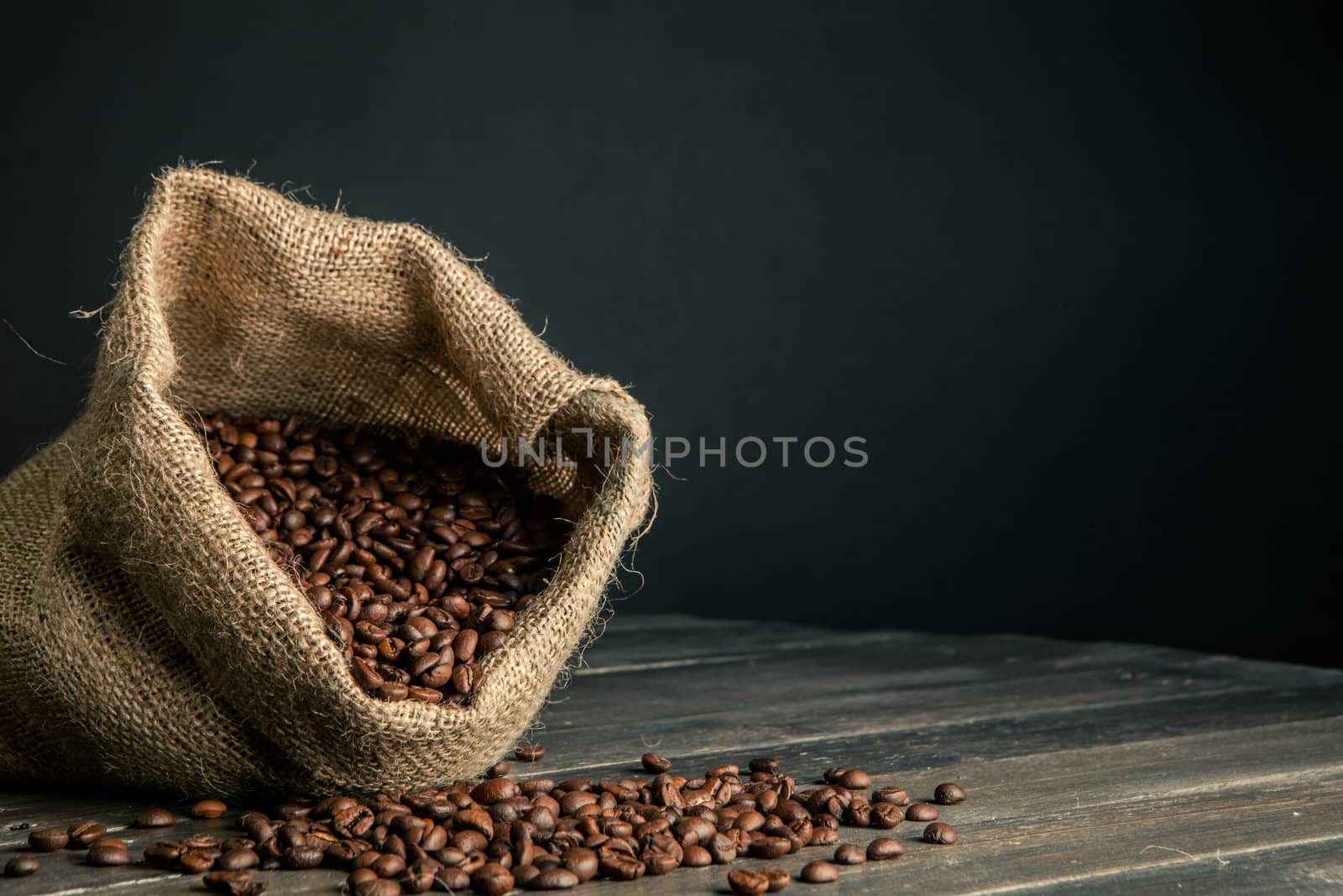 sack made by jute full of coffee beans,scattered on a wooden table