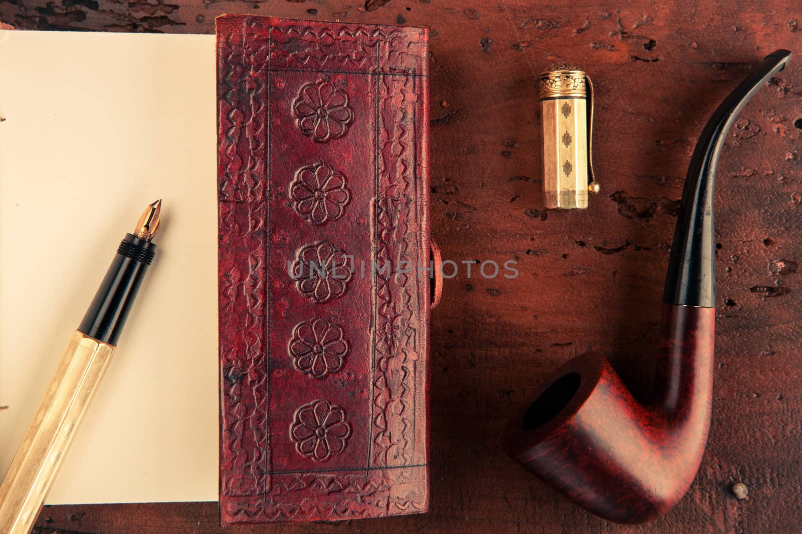 opened notebook and a golden pen to write some ideas and a pipe for inspiration