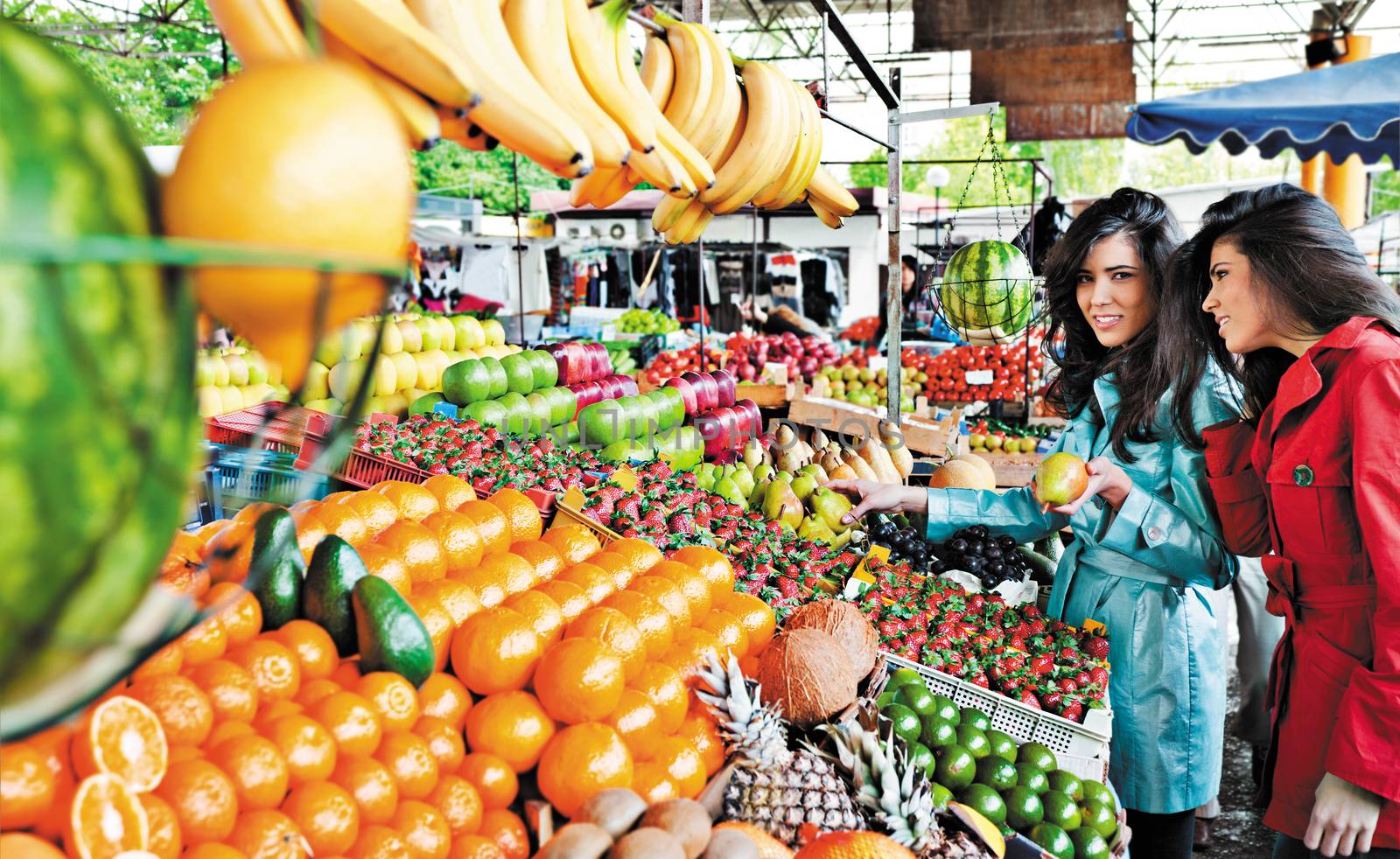 sisters shopping fruits at an outdoors farmers market