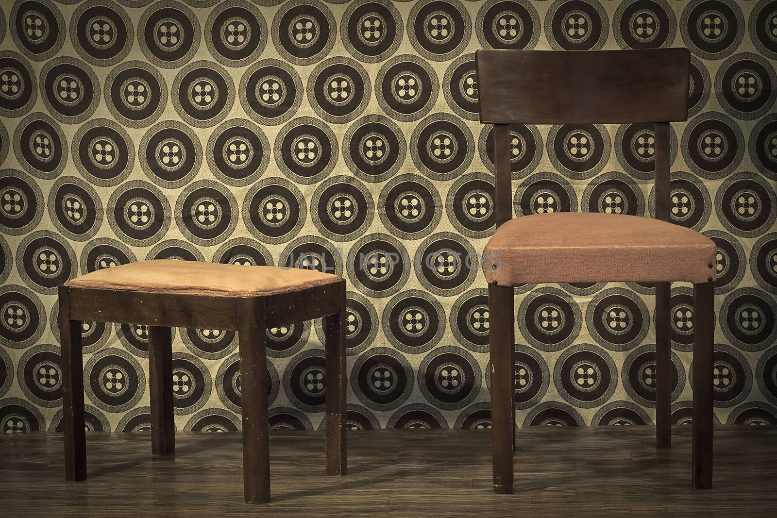 old chair and footrest in a retro room with parquet and and wall paper