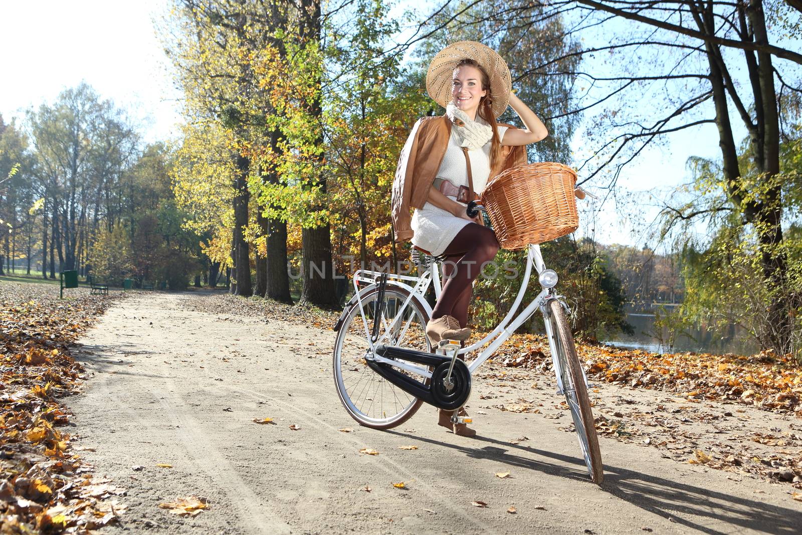 girl on a bicycle in a park alley background color of autumn leaves