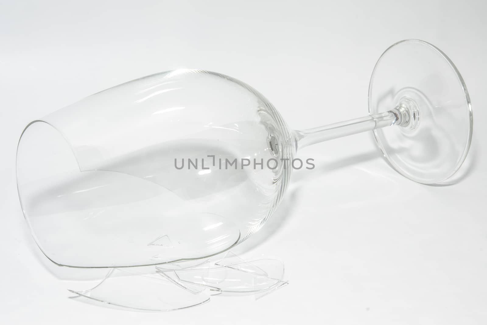 Shattered broken-down wine glass with sharp shards lying on white background