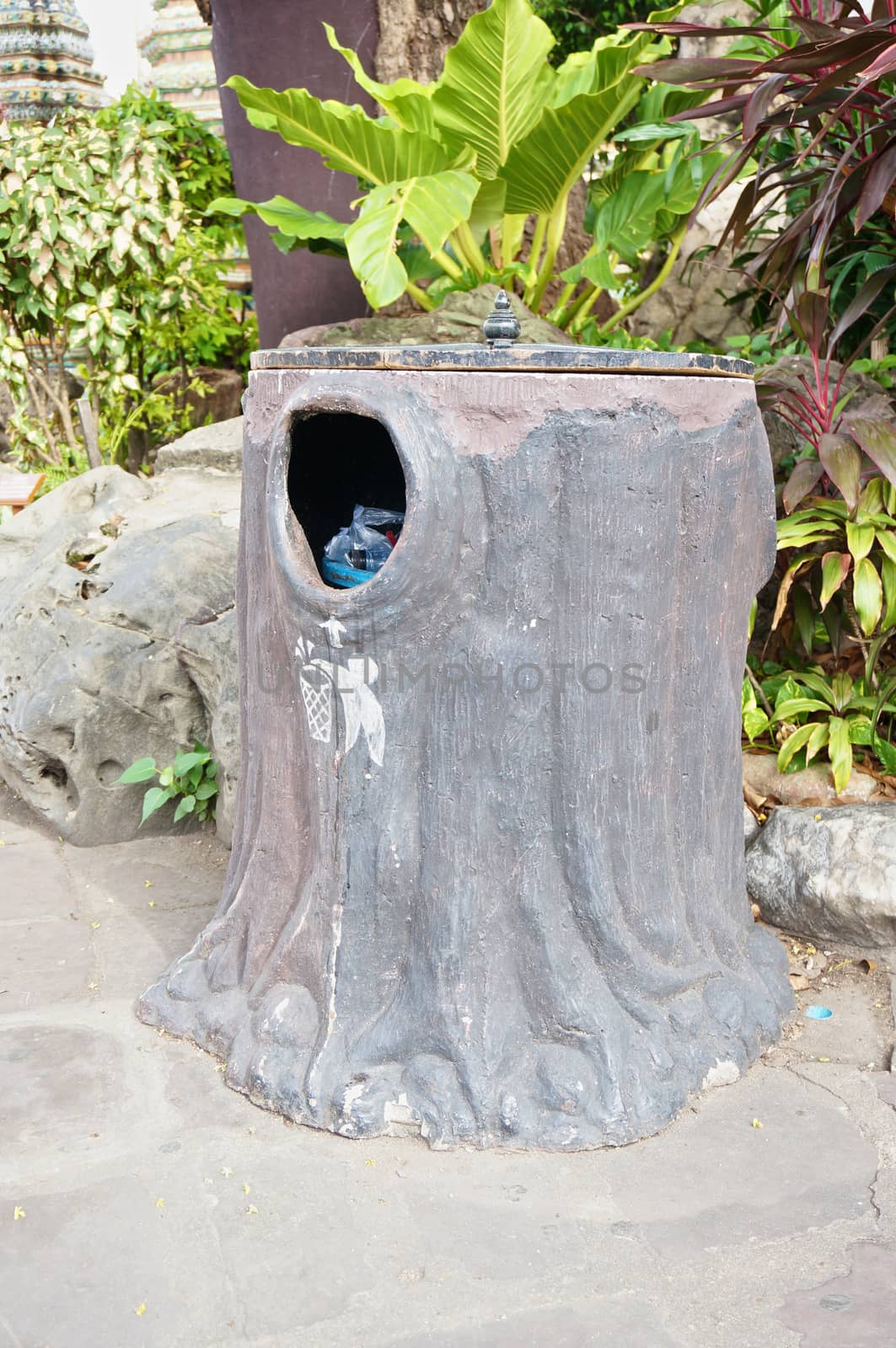 Bin like stump made by cement has wood lid on top.