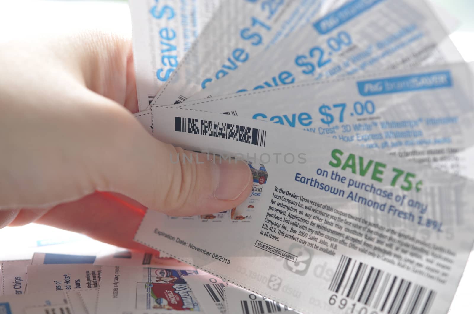 Coquitlam, BC, Canada - May 25, 2014 : Close up holding saving coupons. All coupons for Canadian store, they are issued by manufacturers of consumer packaged goods or by retailers in Canada.