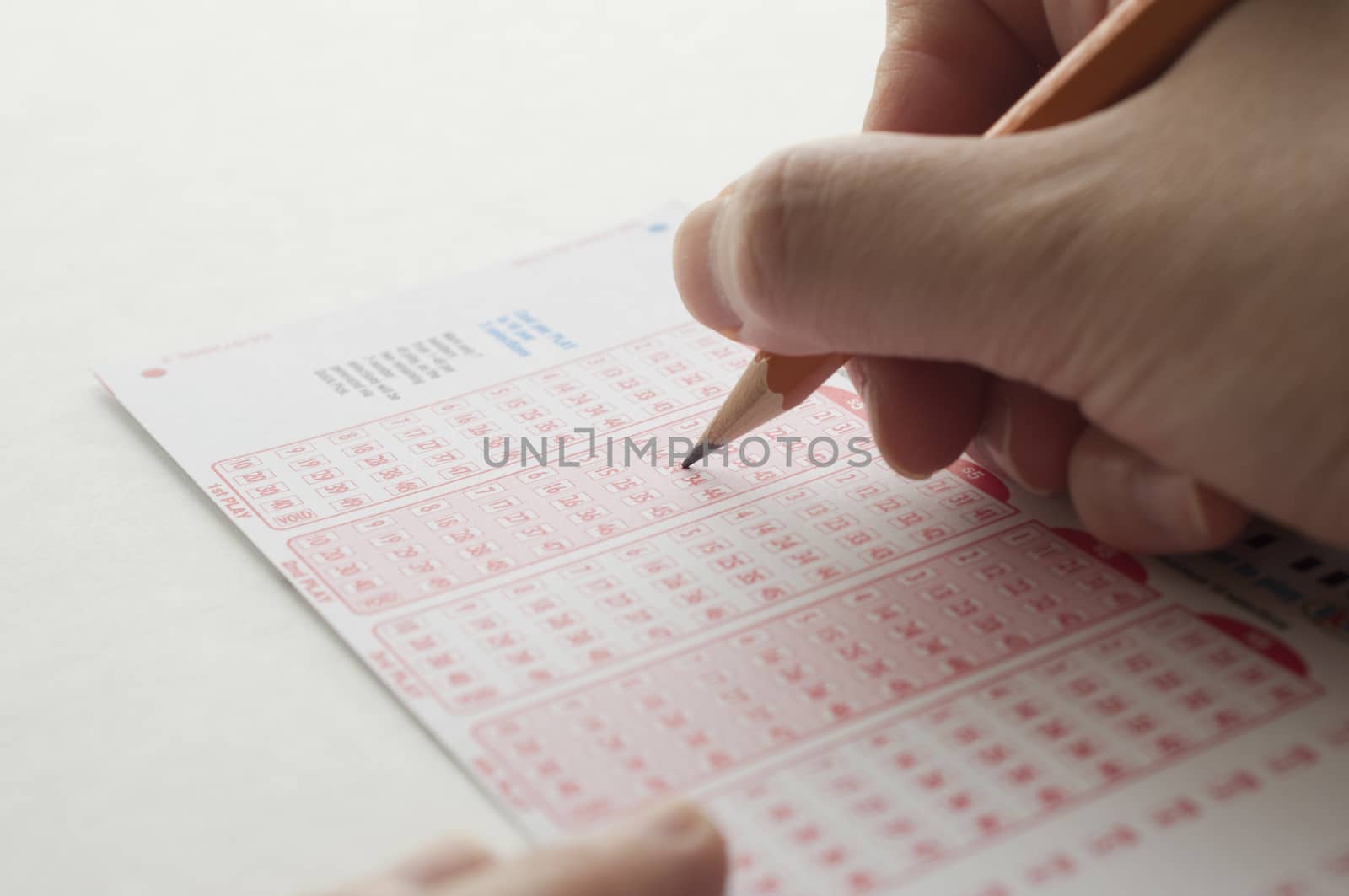 Close-up of a person marking number on lottery ticket with pen