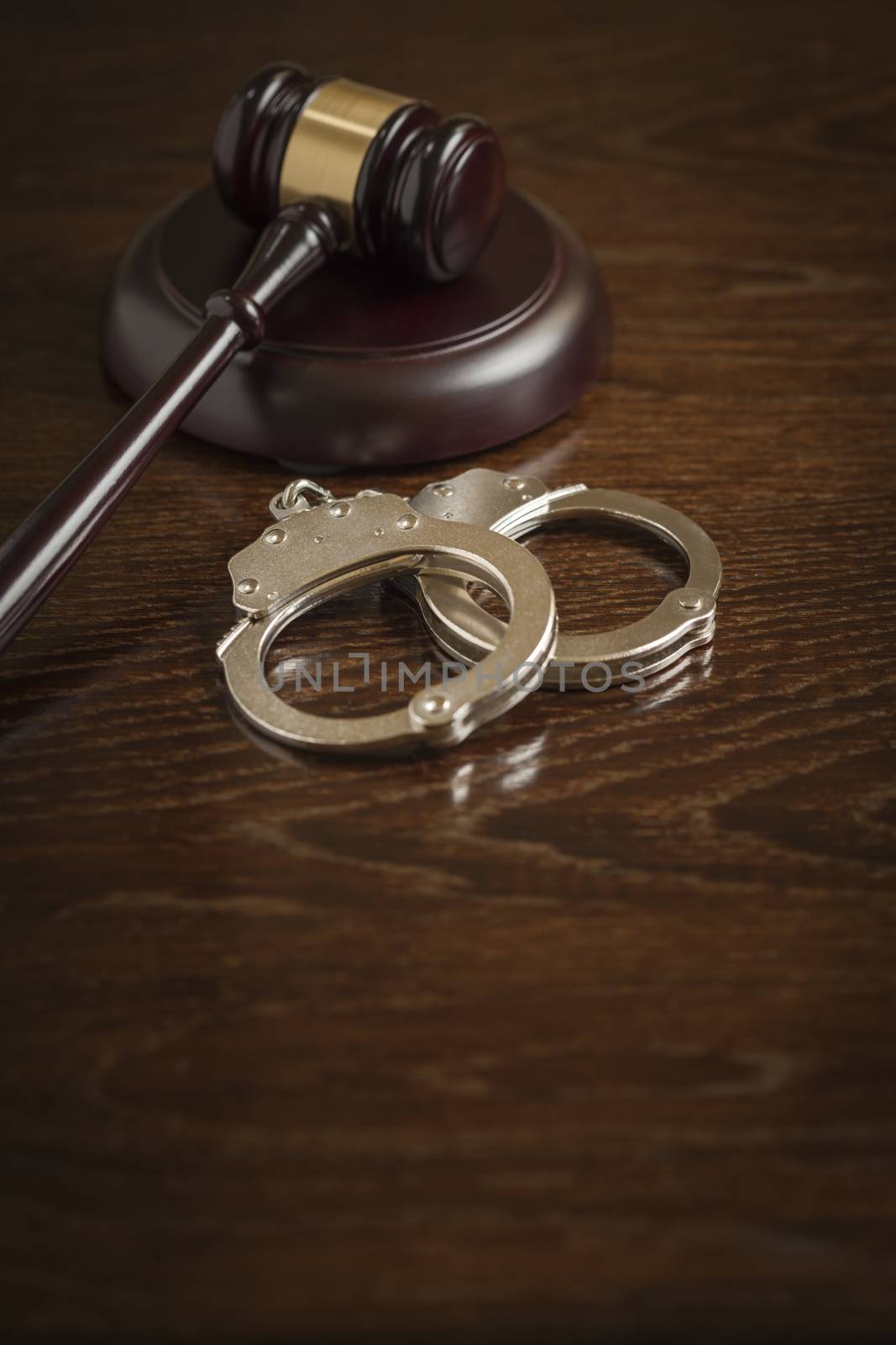 Gavel and Pair of Handcuffs on Wooden Table.