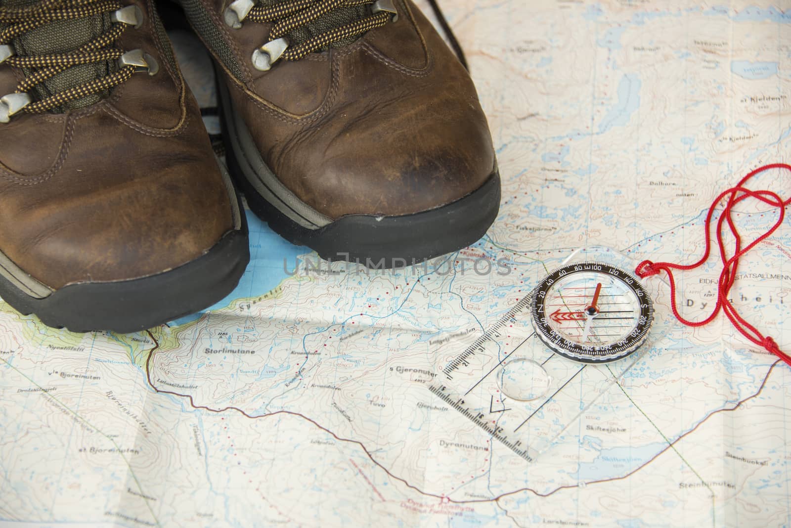 Old hinking boot on a map and compass by GryT