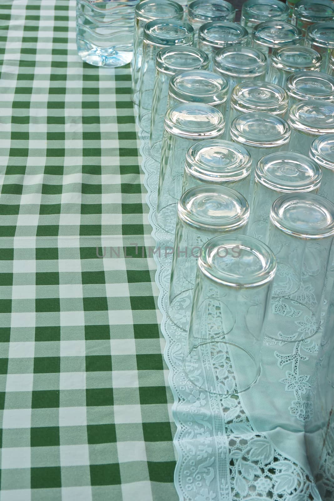 Empty glass upside down on a table covered by a green and white stripes.