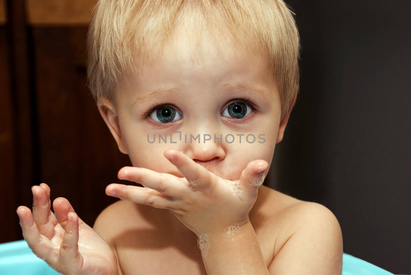 Little funny boy with a funny expression on his face washed in the bath.