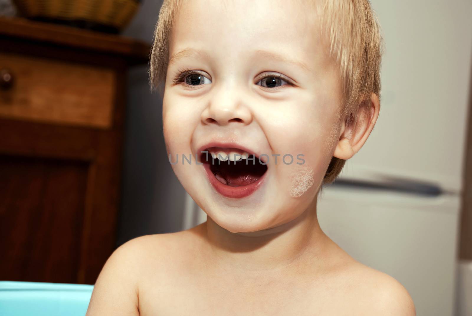 Little funny boy with a funny expression on his face washed in the bath.