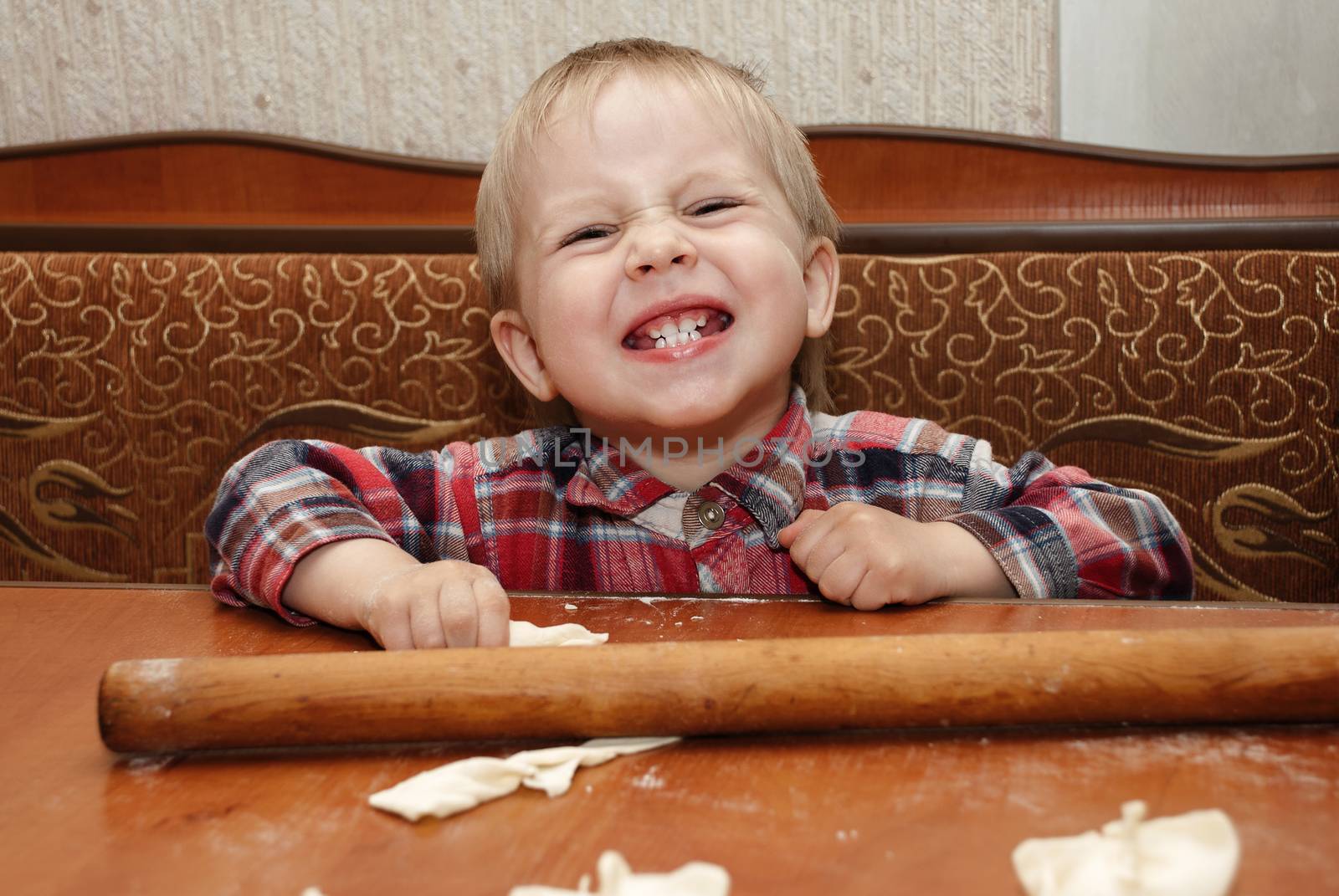 Little funny boy in the kitchen engaged in cooking