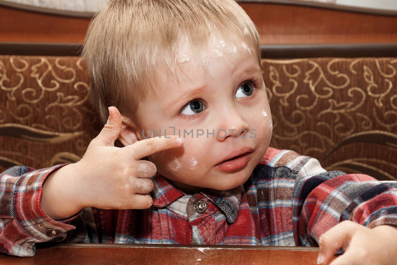 Little funny boy in the kitchen engaged in cooking