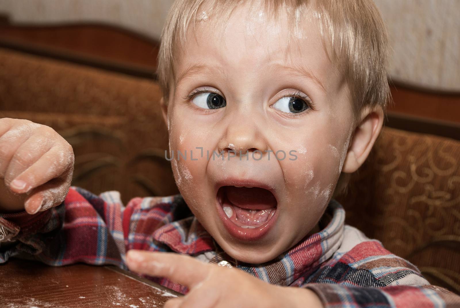 Little funny boy in the kitchen engaged in cooking