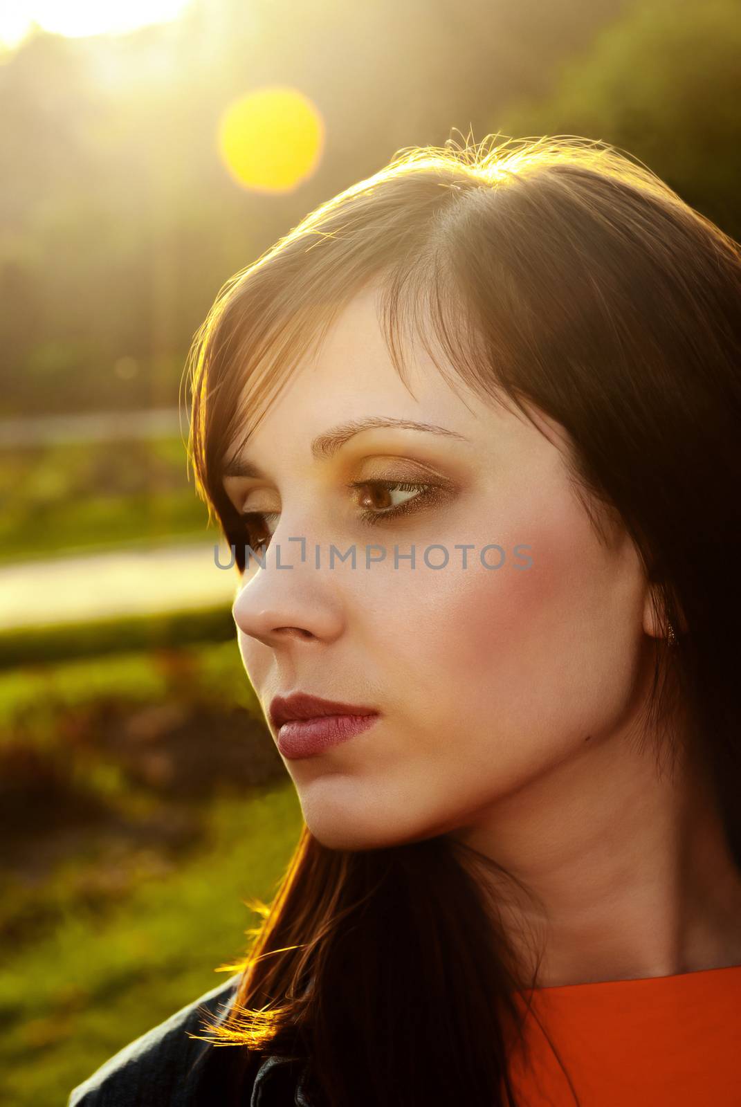 Beautiful female face outdoors back lit sunlight.