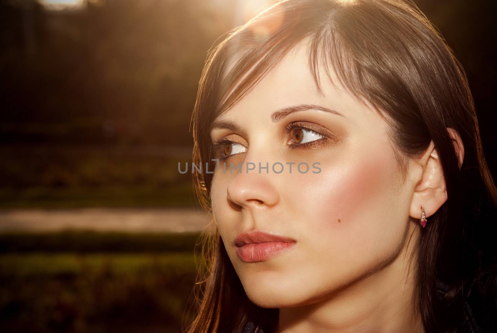 Beautiful female face outdoors back lit sunlight.