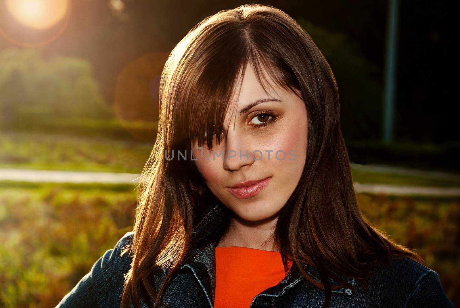 Beautiful female face outdoors back lit sunlight.