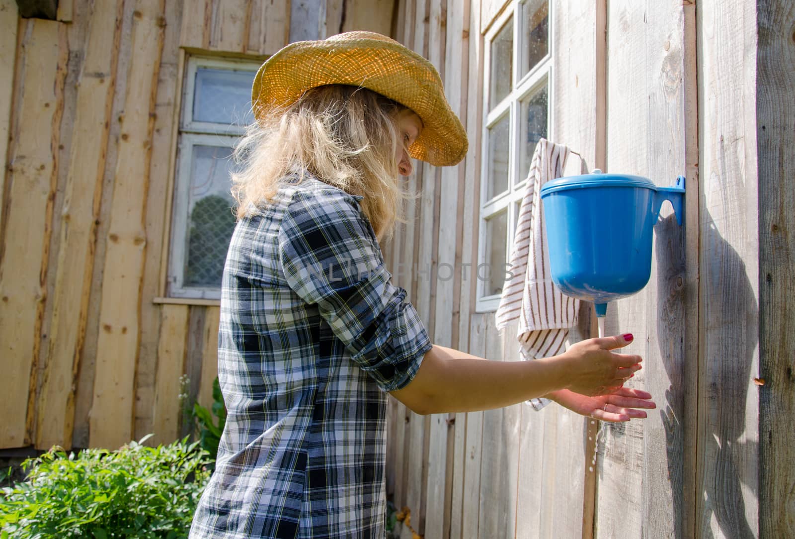 farmer cowgirl woman wash hands under rural plastic hand washer tool water.