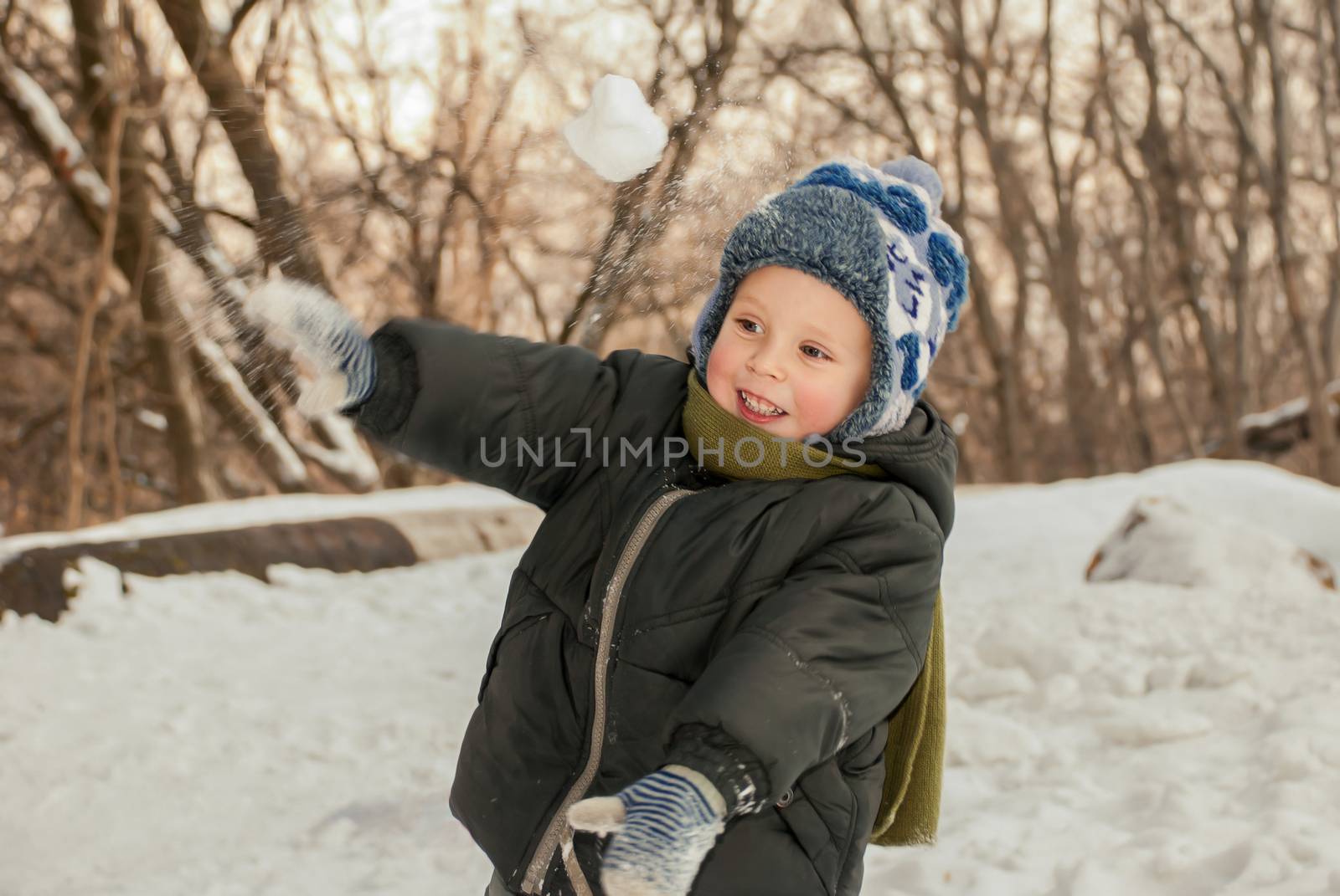 Little boy playing in the snow outdoors in winter.
