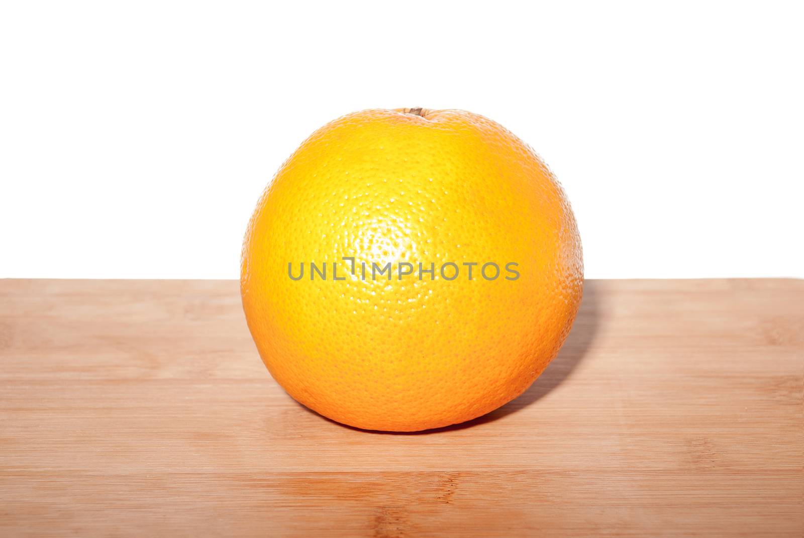 Ripe grapefruit on a wooden board with white back background.