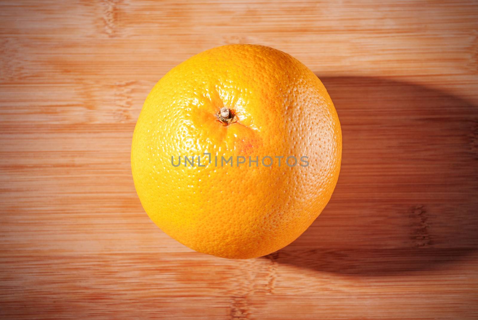 Ripe one grapefruit on wooden board.