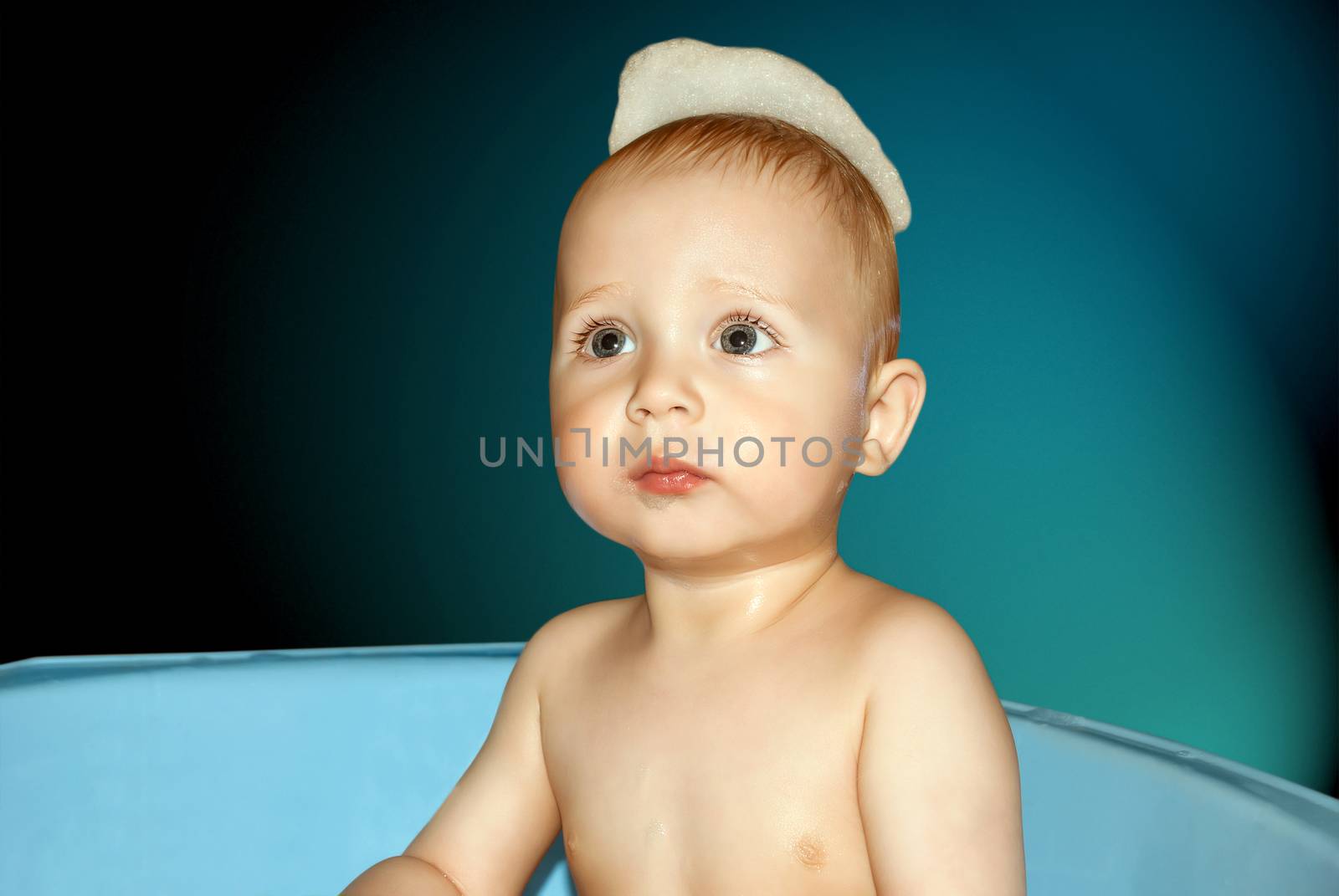 Baby face close-up bathing in the tub.